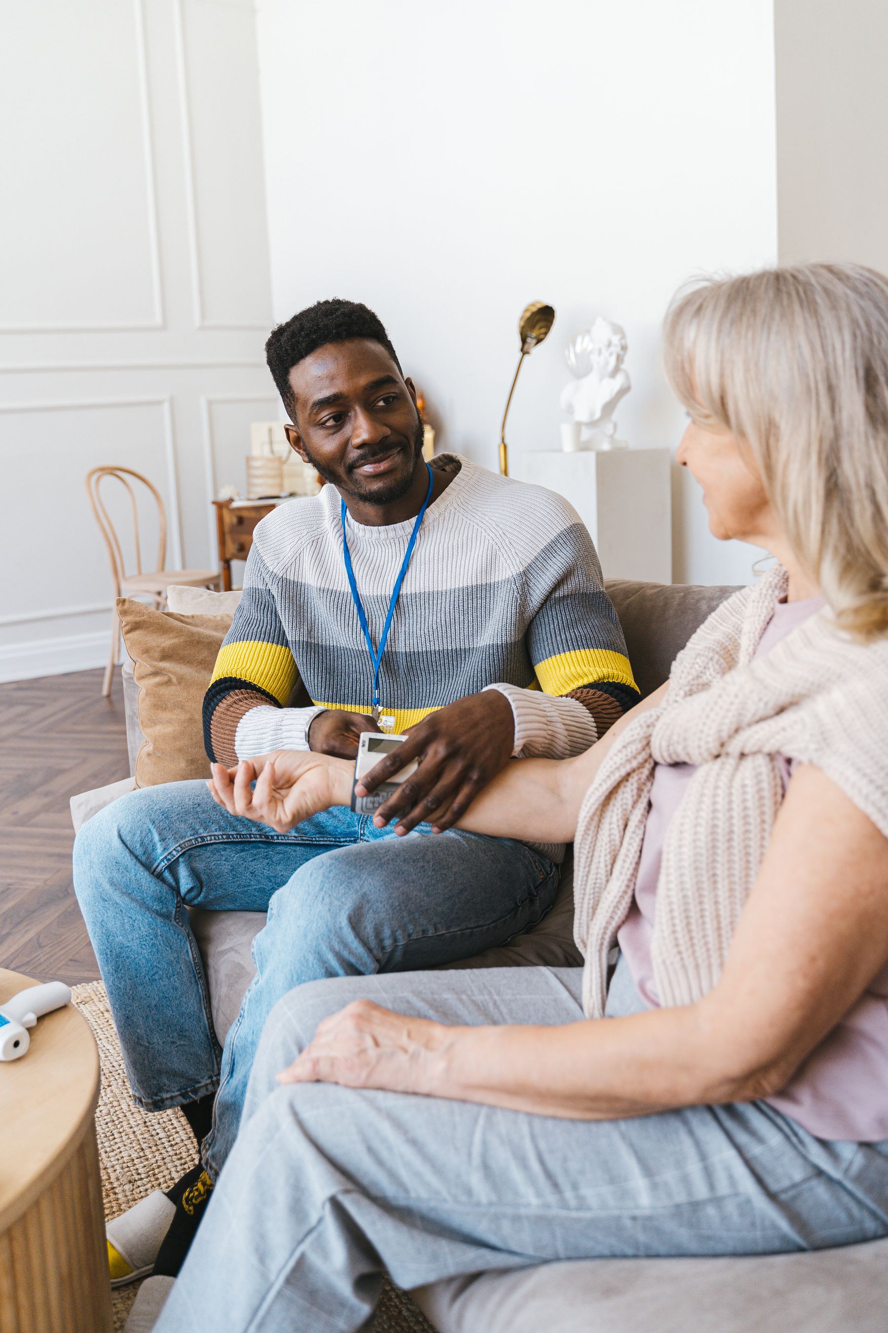 Caregiver taking a blood-pressure reading on a couch at home